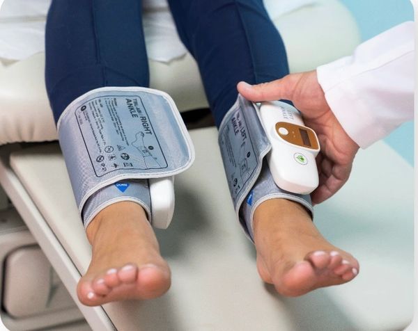 Person receiving ankle blood pressure measurement with a medical device.