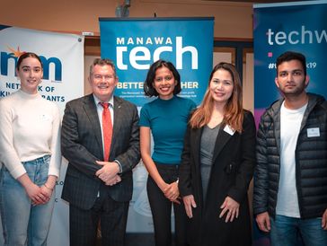 Five professionals posing at a tech networking event.