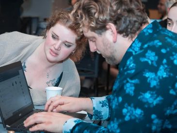 Two people collaborating on a laptop with focused expressions.