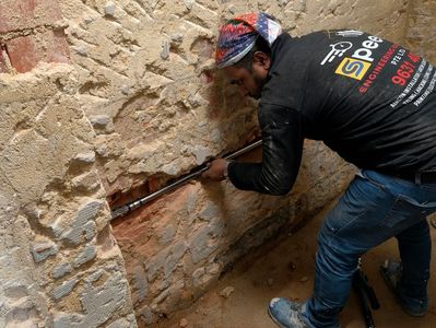 Man using a tool on a brick wall.