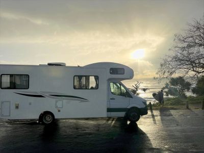 A camper van parked near a beach at sunset.