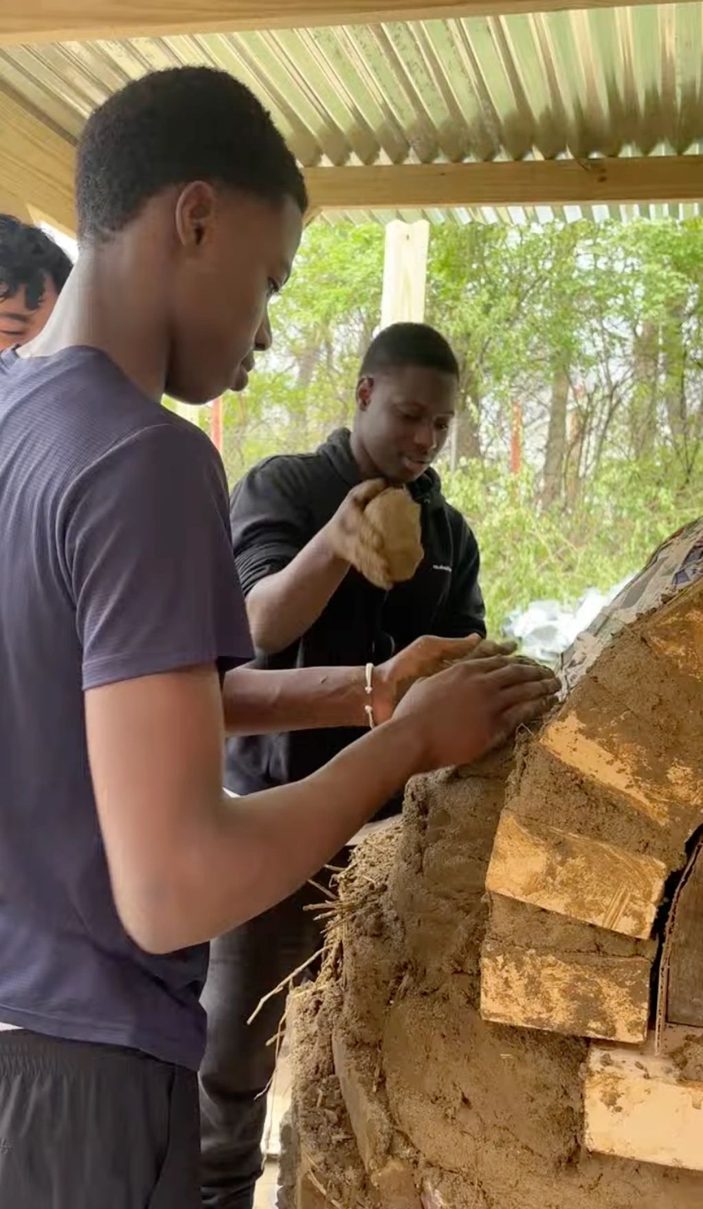 Dater High School students using a natural mixture of clay, sand and straw to build their outdoor co