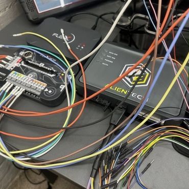 Complex wiring setup with diagnostic devices and multicolored cables on a desk.