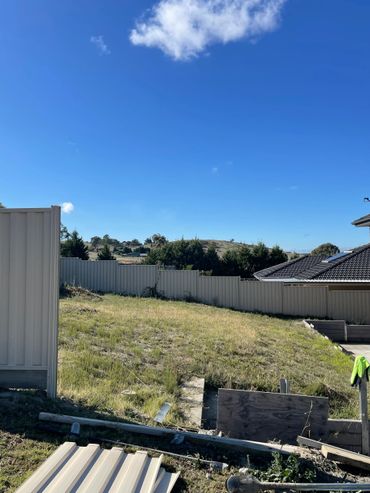 Empty backyard with partial fencing and clear blue sky.