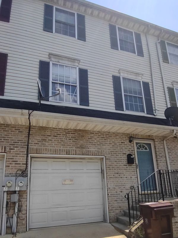 Three-story townhouse with garage and blue front door under clear sky.