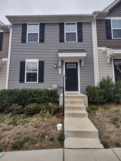 Two-story gray townhouse with black door and windows.