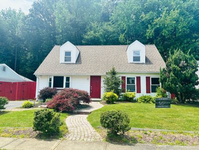 Charming white house with red accents and lush green lawn.