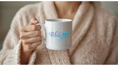 Person holding a white mug with 'Whole You' logo, wearing a cozy beige knitted sweater.