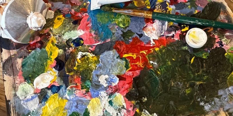 A colorful artist's palette with mixed paints and brushes.