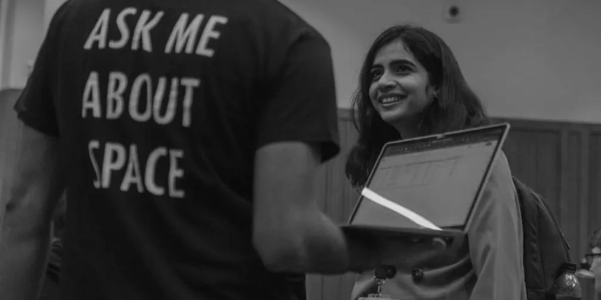Sai Tejaswi discussing with an UKSEDS member wearing a t-shirt "ASK ME ABOUT SPACE"