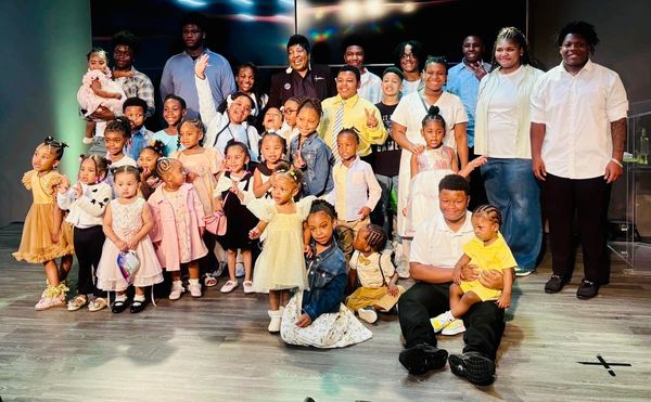 Large group of children and adults posing for a cheerful group photo indoors.