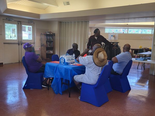 People seated and standing around a table in a community room.