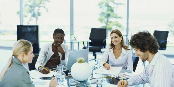 Three women and a man sitting at a table during a meeting