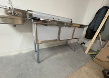 A metal sink with a support frame in a sparse room.