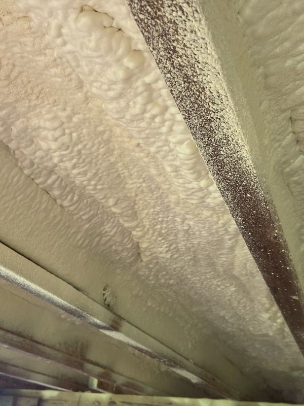 Spray foam insulation applied under a building's floor for thermal protection.