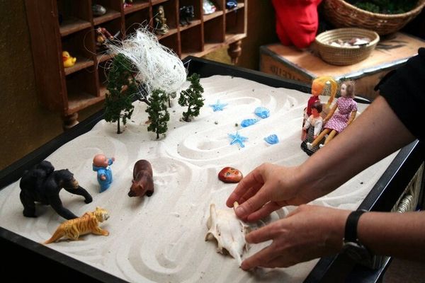 Large sandtray with figurines and miniatures showing mini world of animals, people and trees