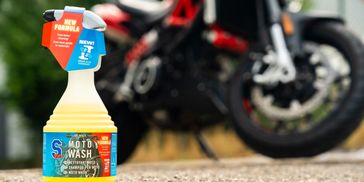 Bottle of motorcycle cleaner with a motorcycle in the background.