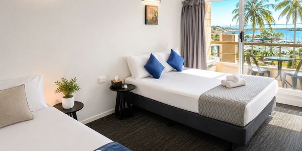 Hotel room with two beds and ocean view balcony.