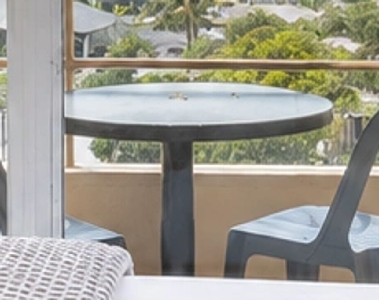 Outdoor table with two chairs on a balcony overlooking greenery.