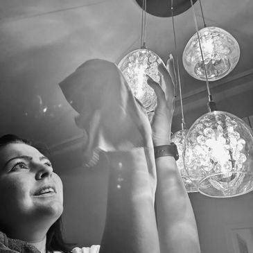 Detailed cleaning of a glass light fitting during a weekly service.