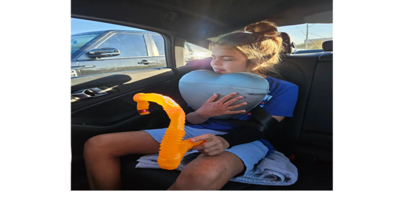 Inside image of a car with a girl sitting along with a pillow