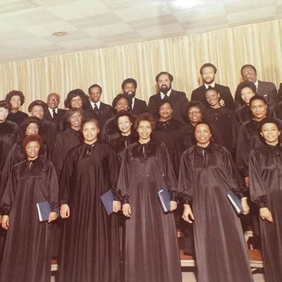 A choir group in black robes posing for a photo.
