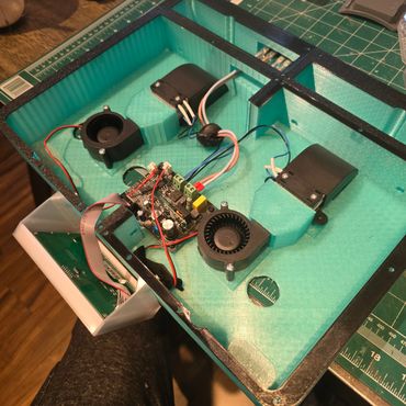 3D printed electronics enclosure with fans and circuit board inside.