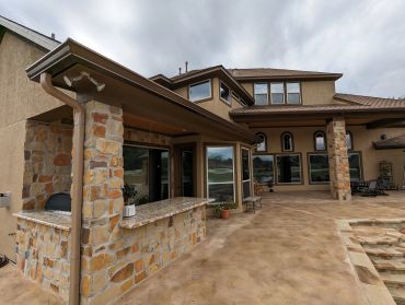 Spacious patio area with stone accents and outdoor seating under cloudy sky.