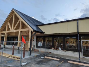 Building undergoing exterior renovation with wooden framing and metal roof.