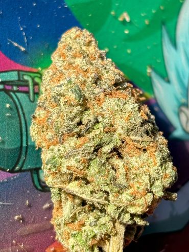 Close-up of a cannabis bud on a colorful surface.