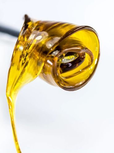 Close-up of golden honey dripping from a utensil on a white background.