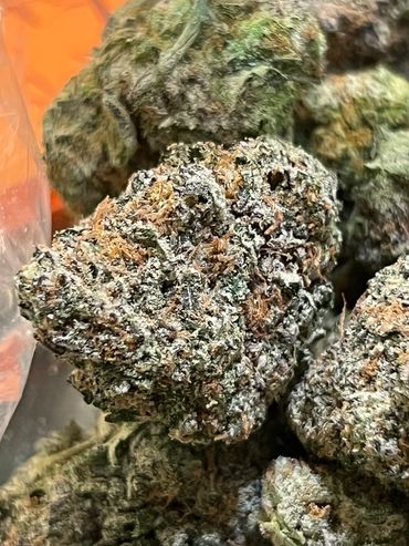 Close-up of dense cannabis buds with trichomes and orange hairs.