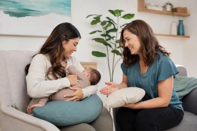 Lactation counselor supporting a mother holding and feeding her baby.