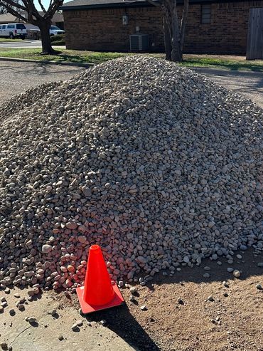 A large pile of gravel surrounded by orange traffic cones.