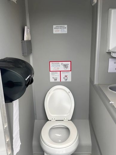 Public restroom with an open toilet and paper towel dispenser.