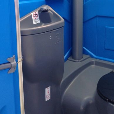 Interior of a portable toilet showing a hand sanitizer dispenser.