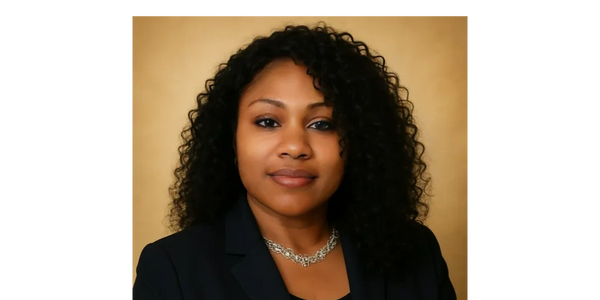 Professional portrait of a confident woman with curly hair and a black blazer.