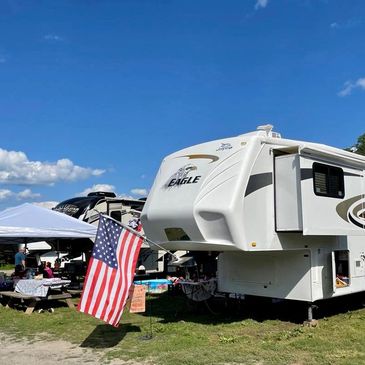 A 5th wheel camper with an American flag flying off the front.