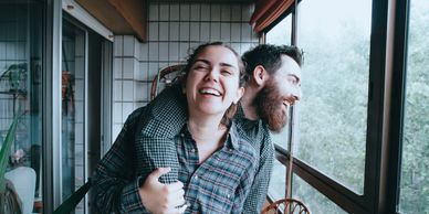 A couple hugging and laughing in their kitchen while looking outside