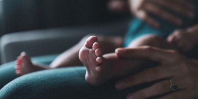 A mother holding her baby with the babies feet in focus