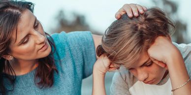 Mom consoling her son while going through a hard time looking down at the ground