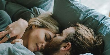 A couple waking up together in bed while man kisses women's forehead