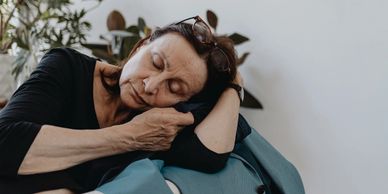 Older women grieving loss while laying on a males sport jacket on couch