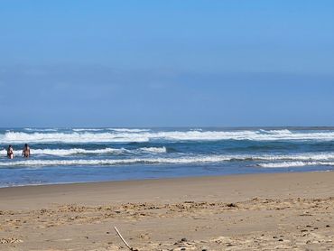 Two people wading into the ocean on a sunny beach day.