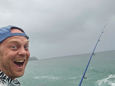 Excited man fishing by the ocean on a cloudy day.