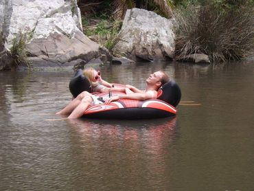 Two people relaxing on an inflatable tube in a calm river.