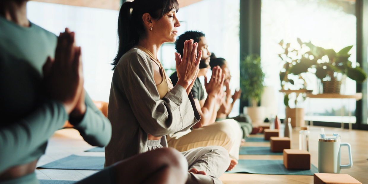 Group of people meditating in a serene yoga studio with natural light.
