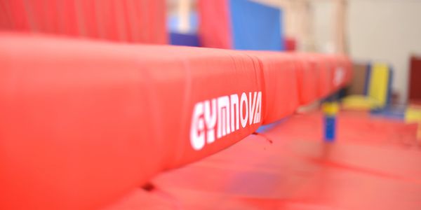 Close-up of a red Gymnova balance beam in a gym.