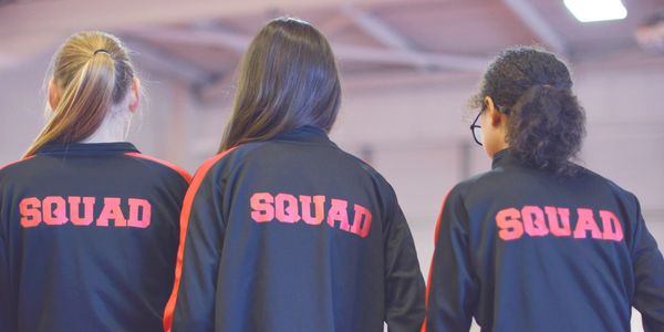 Three people wearing jackets labeled "SQUAD" on the back.