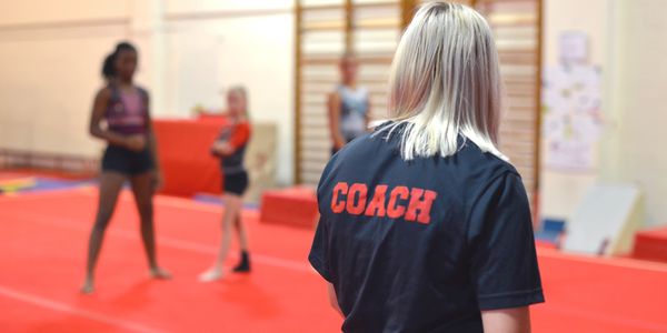 Coach observing gymnasts during practice.